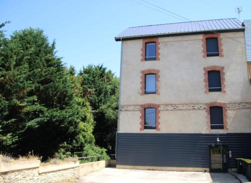 an old building with a gate and trees at Appartement duplex dans une ancienne usine in Beaupréau