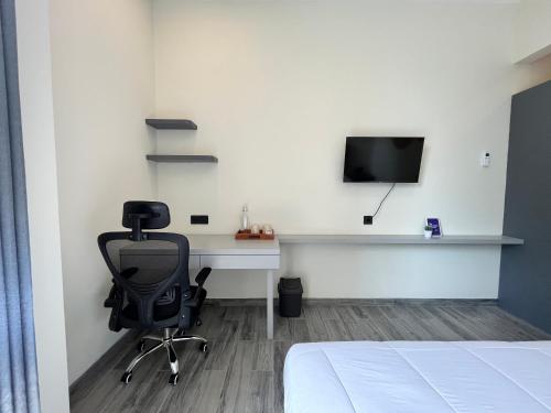 a bedroom with a desk with a chair and a tv at Cove Legacy in Jakarta