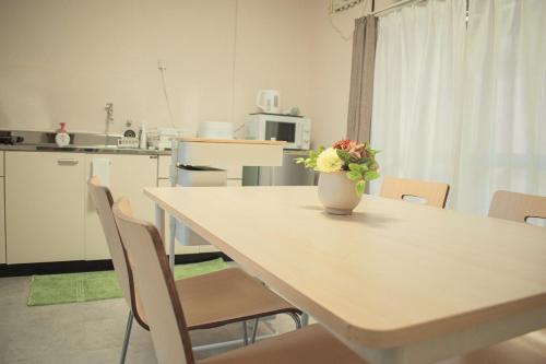 eine Küche mit einem Tisch mit einer Vase mit Blumen darauf in der Unterkunft 折り鶴 Orizuru Guest House in Kyoto