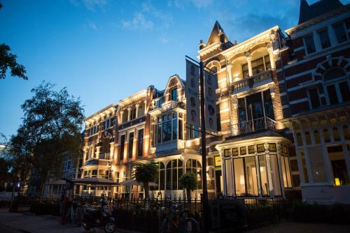 a large white building with a fence in front of it at Boutique Hotels MANNA & Blue in Nijmegen