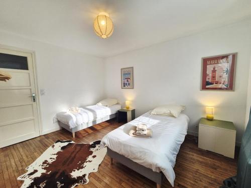 1 dormitorio con 2 camas, 2 lámparas y alfombra en Parenthèse à l'Oasis, en Ploërmel