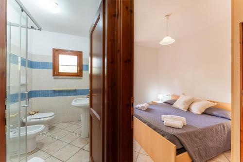 a bedroom with a bed and a bathroom with a toilet at Le Dimore di Budoni in Budoni