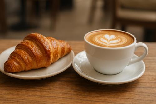 uma chávena de café e um croissant numa mesa em La dolce vita Napoli em Nápoles