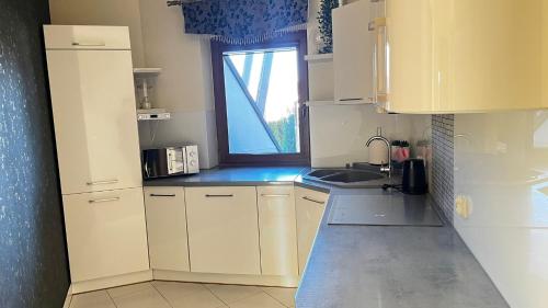 a small kitchen with white cabinets and a window at Willa Sulejowka in Poronin