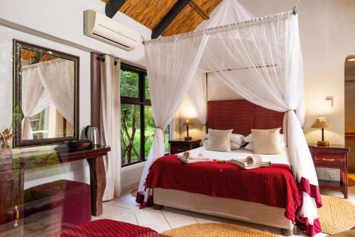 a bedroom with a canopy bed and a large window at Lodge Forest Suite in Hluhluwe