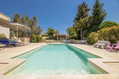 a swimming pool in a yard with chairs and an umbrella at Villa Enea in Poggiardo