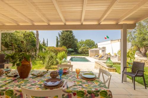 a patio with a table and chairs and a pool at Villa Enea in Poggiardo