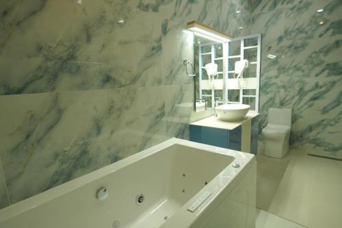 a bathroom with a tub and a sink and a toilet at Winspark Inn Resort in Varkala
