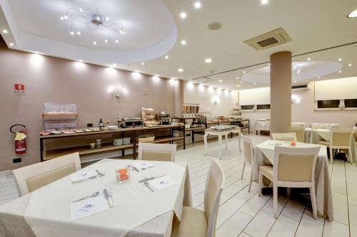 un restaurante con mesas blancas y sillas blancas en Hotel Europa, en Desenzano del Garda