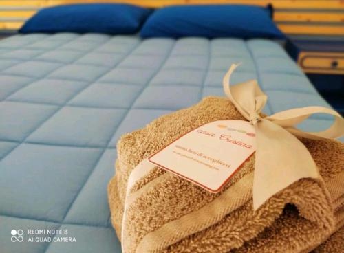 a bed with a towel with a tag on it at Casa Cristina City in Comiso