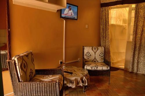 a living room with two chairs and a tv on the wall at Pine Breeze Getaway LUKENYA in Athi River