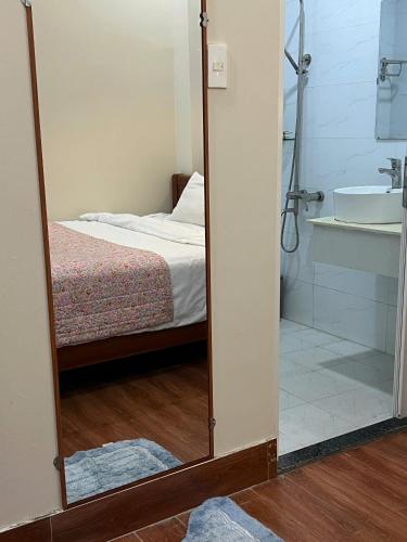 a mirror in a bedroom with a bed and a tub at CaRa Hotel Đà Lạt in Da Lat