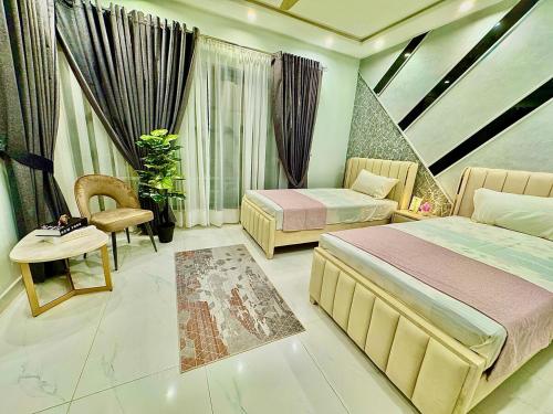 a bedroom with two beds and a table and a chair at 3BR Modern Home Fast Wi-Fi & Parking DHA 9 in Lahore