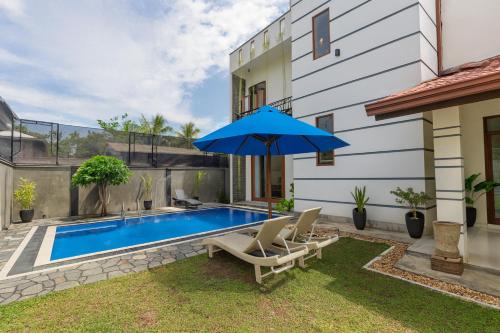 a backyard with a swimming pool and a blue umbrella at Sapphire Escape - Private Villa in Ambalangoda in Ambalangoda