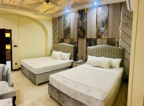 a hotel room with two beds and a couch at Hayat Grand Guest House in Islamabad