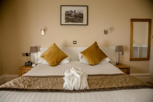 a bedroom with a large bed with yellow pillows at B/W Plus Buxton Lee Wood Hotel in Buxton