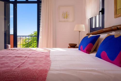 a bedroom with a large bed with blue and red pillows at Villa Flamboyán Meloneras in Meloneras