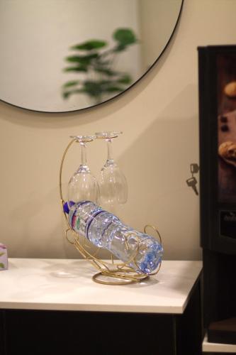 a glass bottle rack with three wine glasses on a table at Spacious Studio with UPS, across Giga mall, Pool included in Islamabad