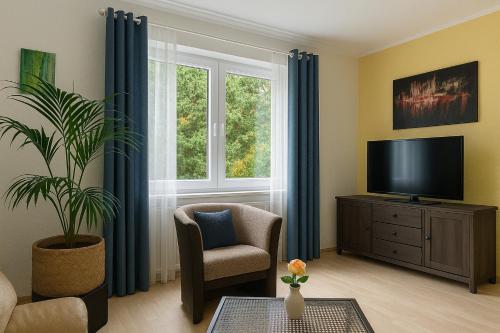 ein Wohnzimmer mit Fernseher, Sessel und Fenster in der Unterkunft VAJAGIC Apartment 2 mit GartenLounge! Messe, Klinikum, Krupp Krankenhaus in Essen
