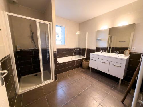a bathroom with a shower and a tub and a sink at Gîte Pégase 
