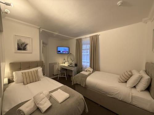a bedroom with two beds and a desk and a television at Central Hotel in Norwich