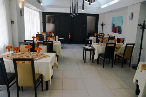 a dining room with white tables and black chairs at Hotel Continental Luanda in Luanda