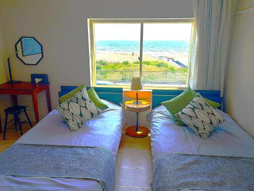 a room with two beds with a view of the ocean at the lounge Kamakura HASE in Kamakura