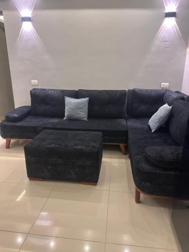 a living room with a black leather couch and stool at Alma & Thiago House in Sharm El Sheikh