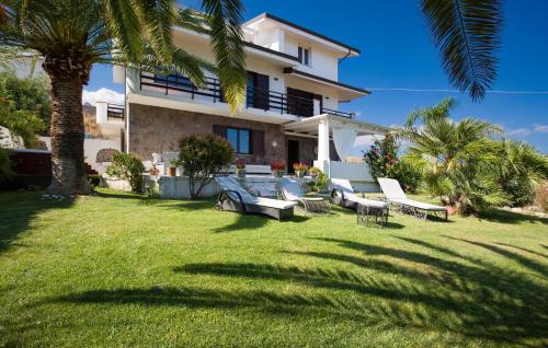 a house with a yard with chairs and a palm tree at Villa Mare Panoramica Estia in Brancaleone Marina