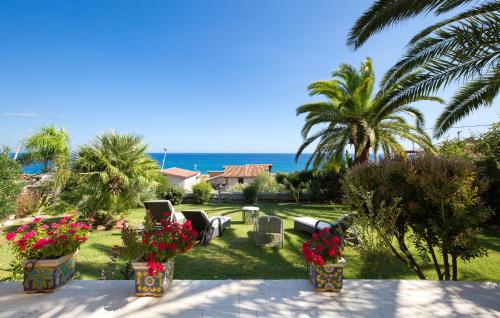 a yard with palm trees and the ocean in the background at Villa Mare Panoramica Estia in Brancaleone Marina