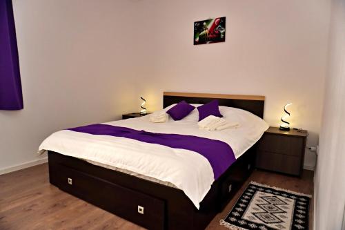 um quarto com uma cama grande com lençóis e travesseiros roxos em FLH - MIG Loft Sibiu em Cisnădie
