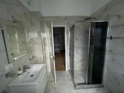 a white bathroom with a shower and a sink at I&O Loft360 in Shkodër