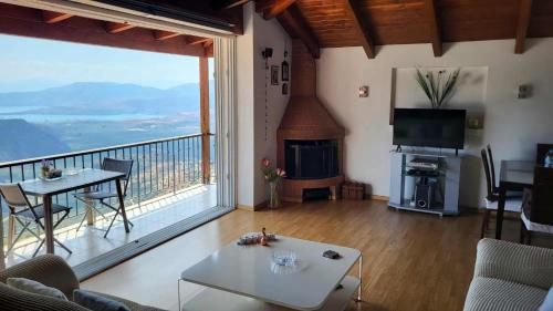 a living room with a fireplace and a large window at skyview house in Delfoi