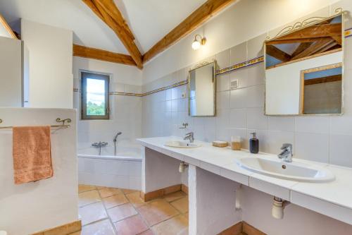 ein weißes Badezimmer mit 2 Waschbecken und einer Badewanne in der Unterkunft Gîte avec piscine de 25 m et spa in Saint-Mathieu-de-Tréviers