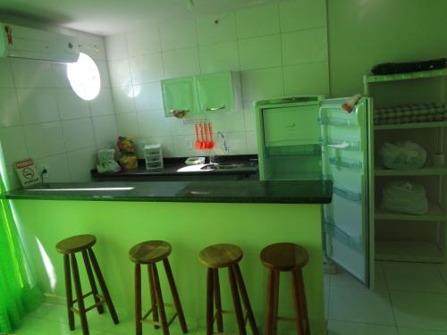 una cocina verde con taburetes frente a un mostrador en Flat Paraty Studio, en Paraty