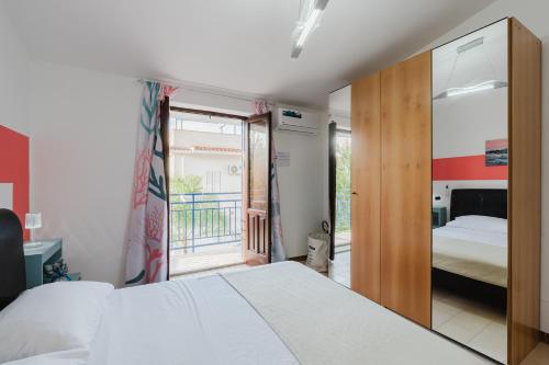 a bedroom with a white bed and a balcony at Venti Del Mare in Trappeto