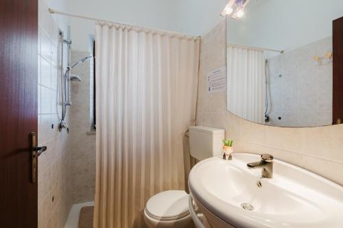 a bathroom with a sink and a toilet and a mirror at Venti Del Mare in Trappeto