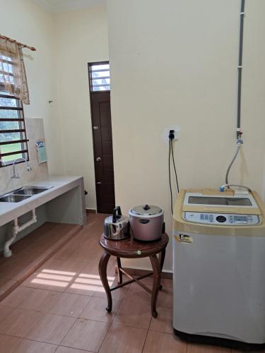 a kitchen with a sink and a table with a stove at Homestay Kubang Kerian, Kota Bharu in Kota Bharu