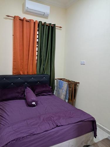 a bedroom with a purple bed with an orange curtain at Homestay Kubang Kerian, Kota Bharu in Kota Bharu