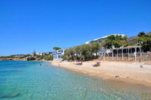 a beach with people in the water and buildings at Paros Seaview Nest - Cozy Summer Getaway in Drios