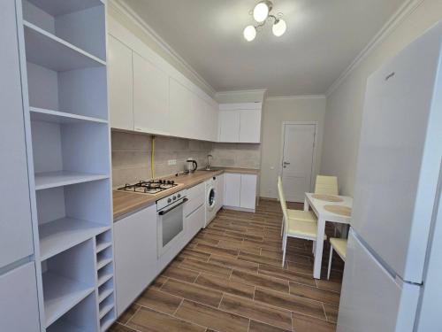 eine Küche mit weißen Schränken und einem Tisch und Stühlen in der Unterkunft Красивая квартира на Телецентре in Chişinău