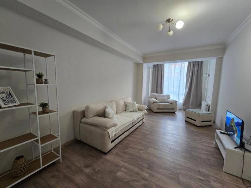 ein weißes Wohnzimmer mit einem Sofa und einem TV in der Unterkunft Красивая квартира на Телецентре in Chişinău