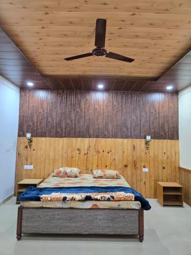 a bedroom with a bed with a ceiling fan at Pinaka Devbhumi Homestay in Mukteshwar