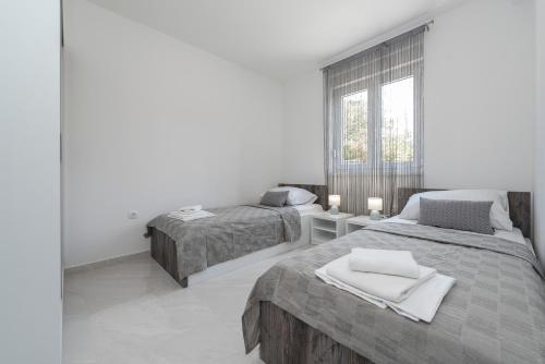 a bedroom with two beds and a window at Villa Mel Mari luxury apartments with pool in Novalja