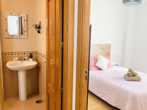 ein kleines Bad mit einem Waschbecken und ein Bett mit einem Waschbecken in der Unterkunft Apartamento San Miguel by At Home Costa del Sol in Nerja