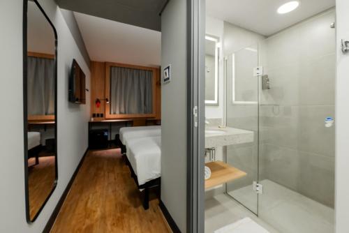 a bedroom with a bed and a sink and a shower at ibis Navegantes Itajai in Itajaí