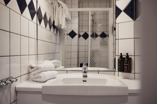 Un baño blanco con lavabo y espejo. en Home Hotel Norre Park, en Halmstad