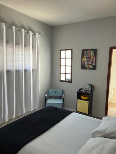 a bedroom with a bed and a chair and a window at Suíte - Centro de Itu in Itu