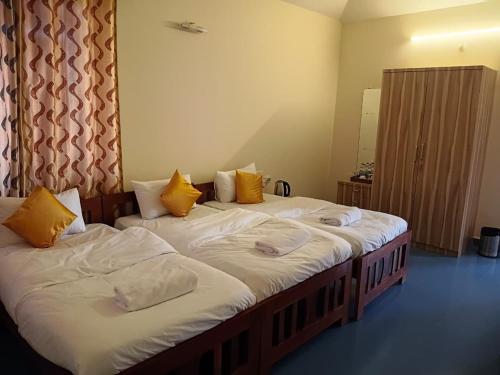 two beds in a room with yellow and white pillows at Dona Helena Holiday Home in Madgaon