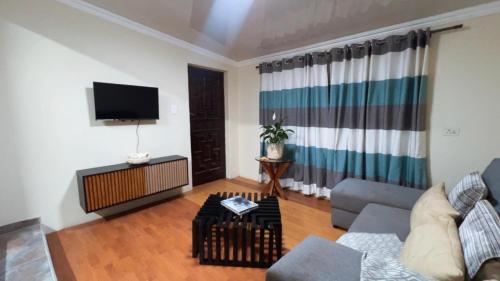 Moya Guesthouse في جوهانسبرغ: غرفة معيشة مع أريكة وتلفزيون